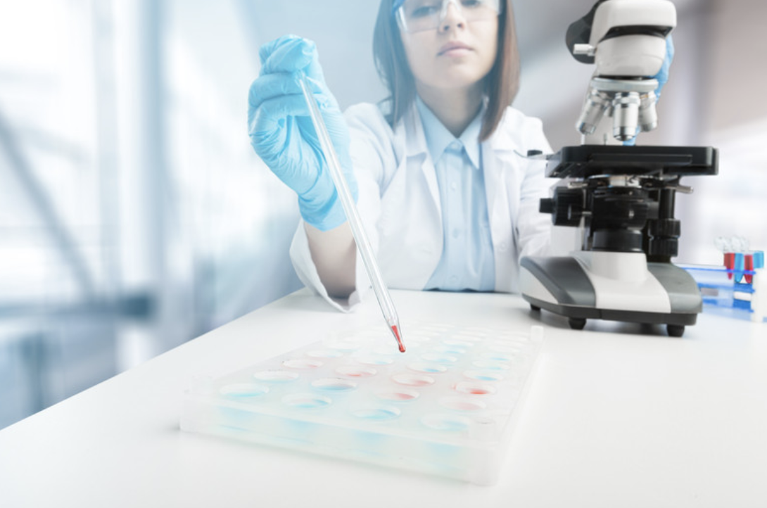Scientist pipetting beside a microscope
